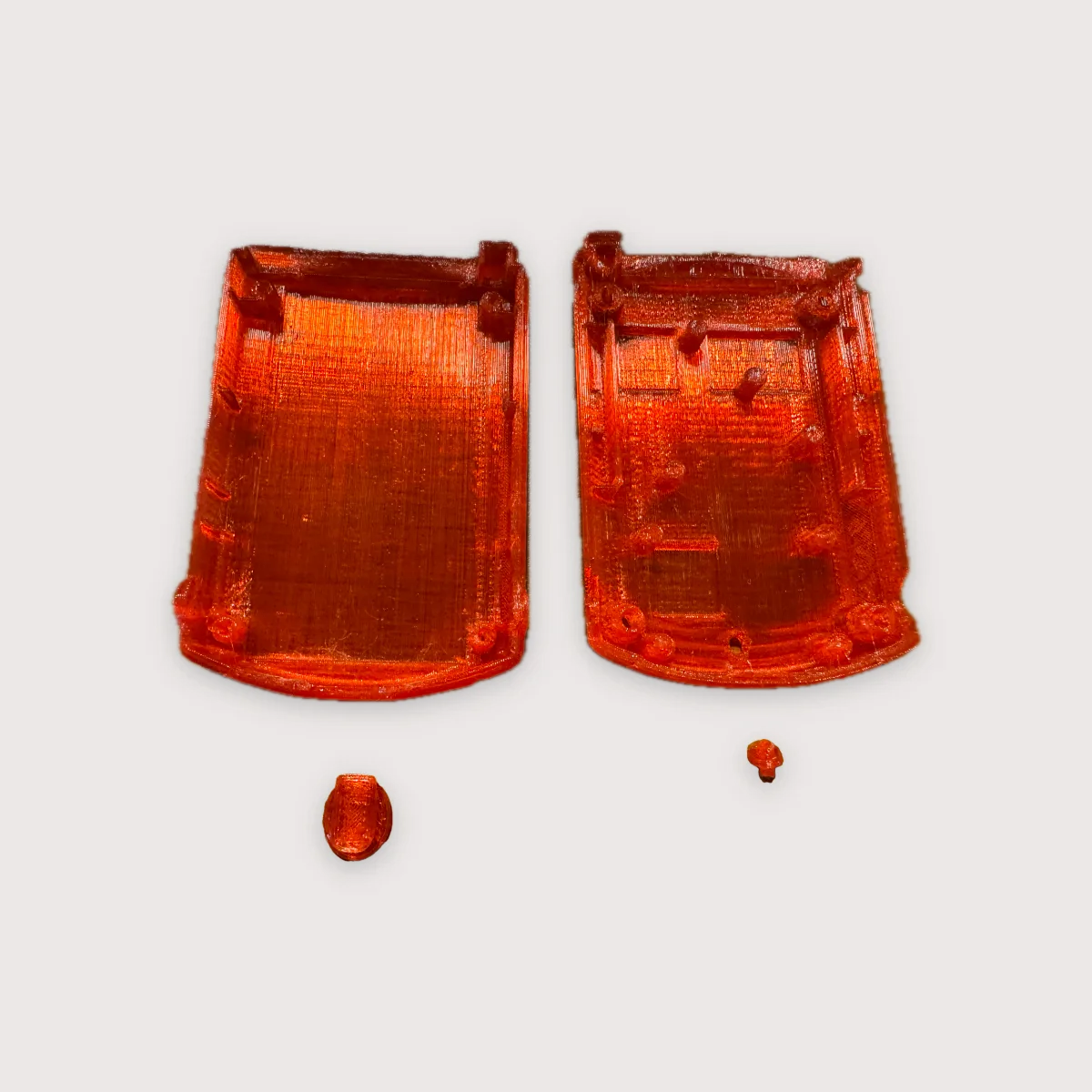 The two halves of the printed Pulsar case, open, with the button plunger and the cable-exit piece beside them